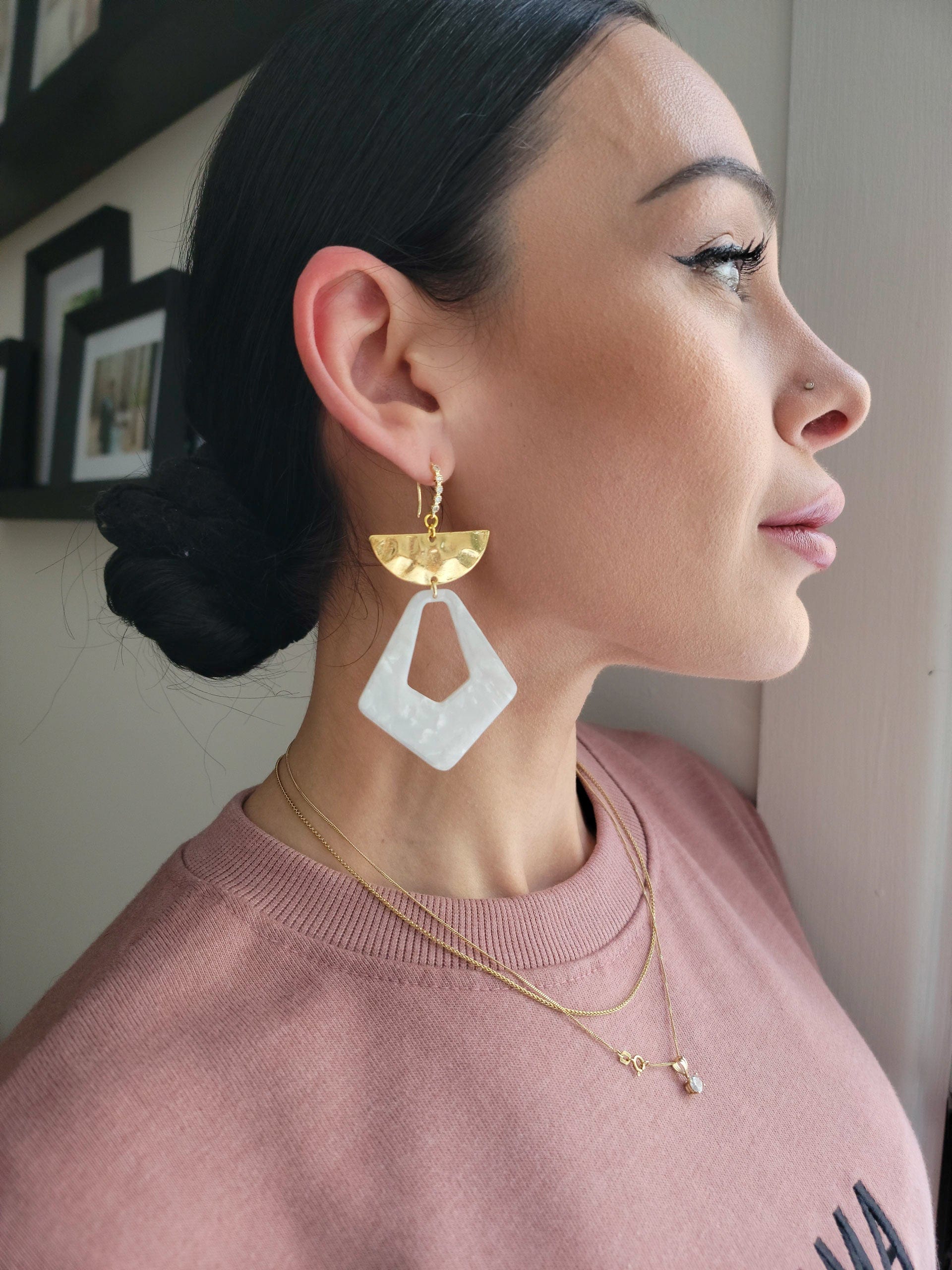 Seren and Skye White Acetate Statement earrings on model. Earrings feature a tear drop space with half-moon hammered gold accent on a cubic-zirconia encrusted ear wire